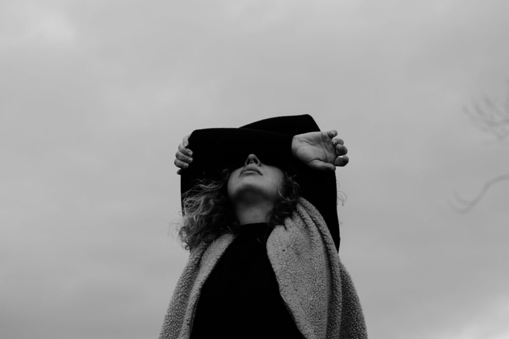 Schwarz-Weiß-Foto: Frau verschränkt die Arme vor dem Gesicht