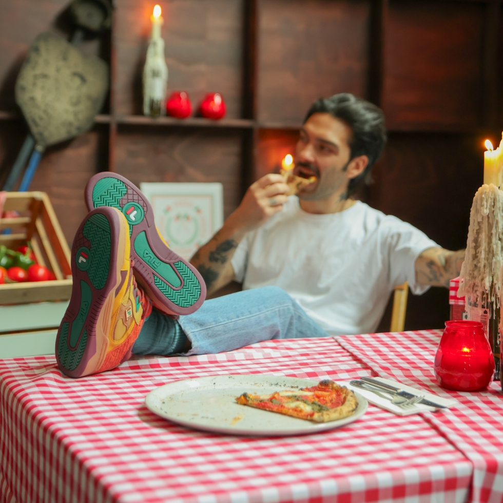 Mann mit Fila Schuhen der Pizza ist