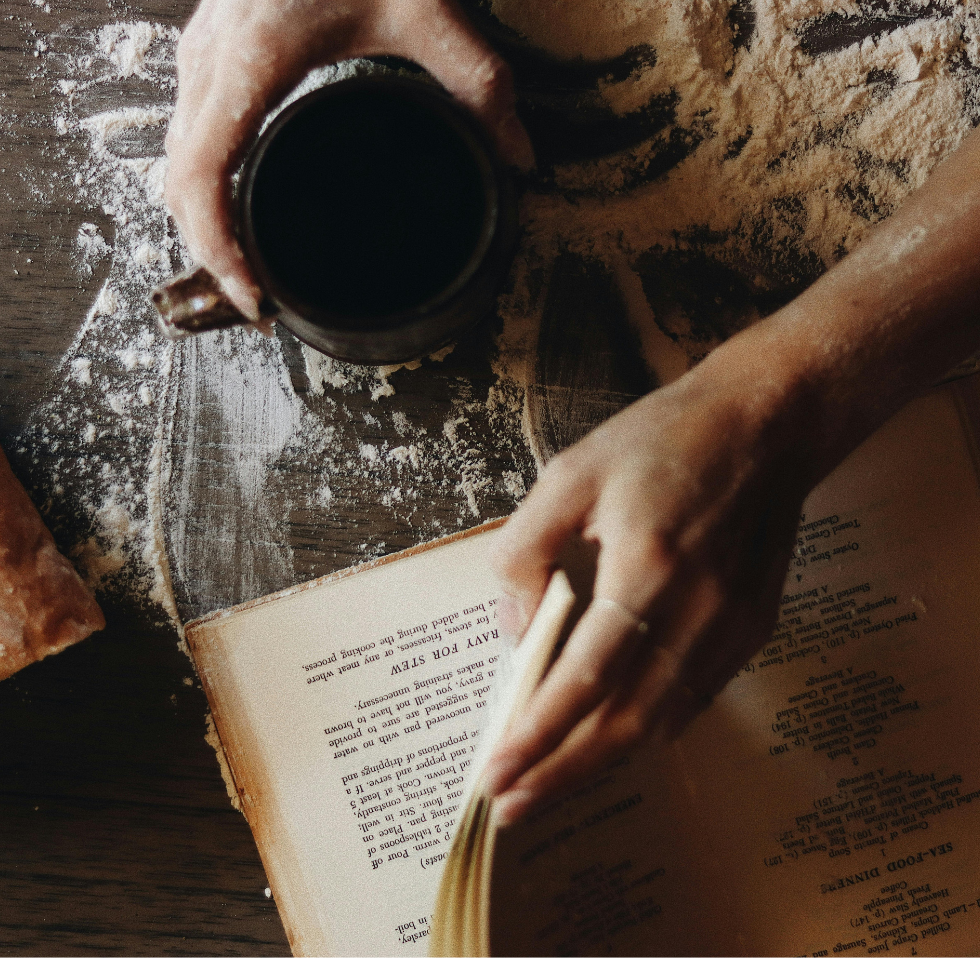 uchtipps Kochen: Hand blättert Rezeptbuch auf mehliger Arbeitsplatte.