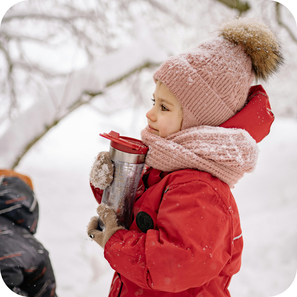 Hysan Salinspray: Ein Kind im Schnee mit Haube, Schal und Skianzug, hält eine Teekanne