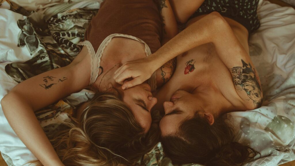 Erotische Filme: junges heterosexuelles Paar liegt im Bett. Er hat die Hand an ihrer Wange.
