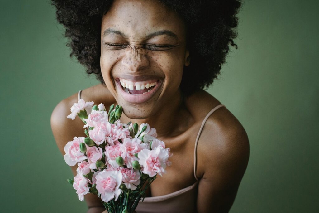 Eine Frau die einen rosa Blumenstrauß in Händen hält und lacht