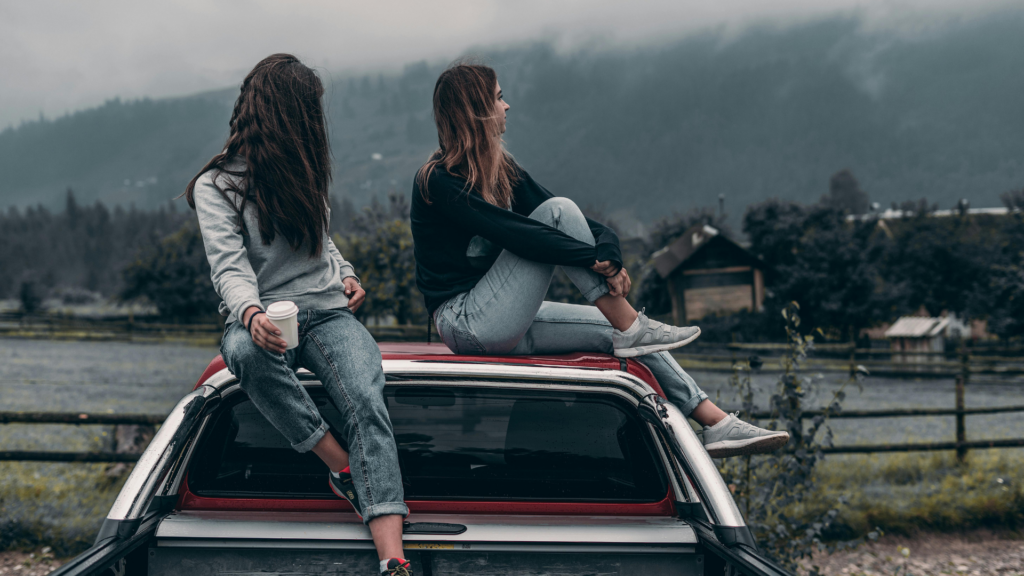 Astrologie Oktober 2025: Zwei Frauen sitzen im Nebel auf einem Autodach