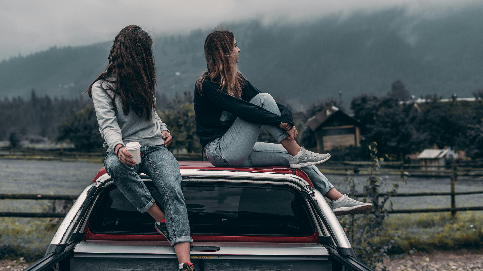 Astrologie Oktober 2025: Zwei Frauen sitzen im Nebel auf einem Autodach