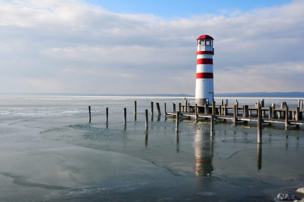 Bewegung im Winter: rot-weiß-gestreifter Leuchtturm an einem angefrorenem See