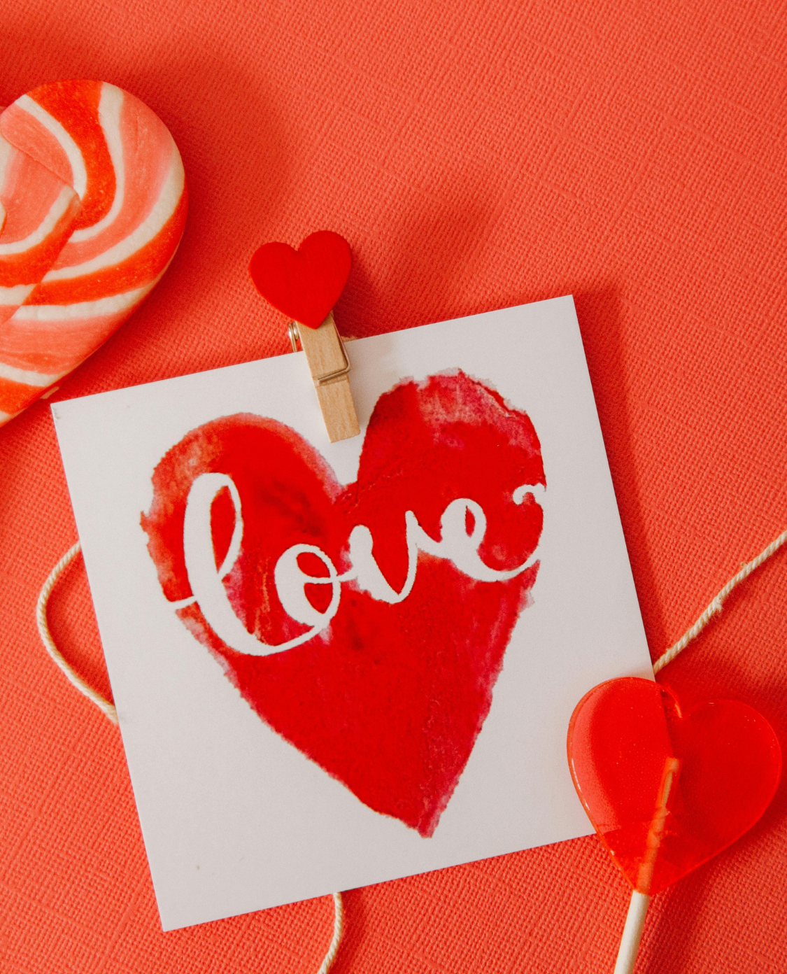 Eine Karte mit einem Herz darauf, worauf "love" zu lesen ist. Vor rotem Hintergrund