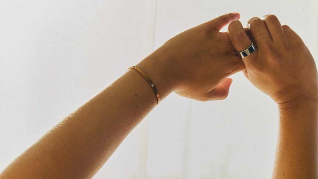 Hochgestreckte Hände mit Oura-Ring am Finger