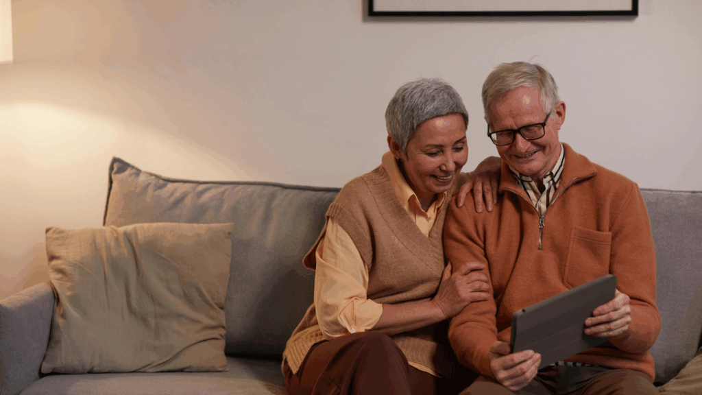 Eine Frau und ein Mann sitzen auf einem Sofa und schauen auf ein Tablet