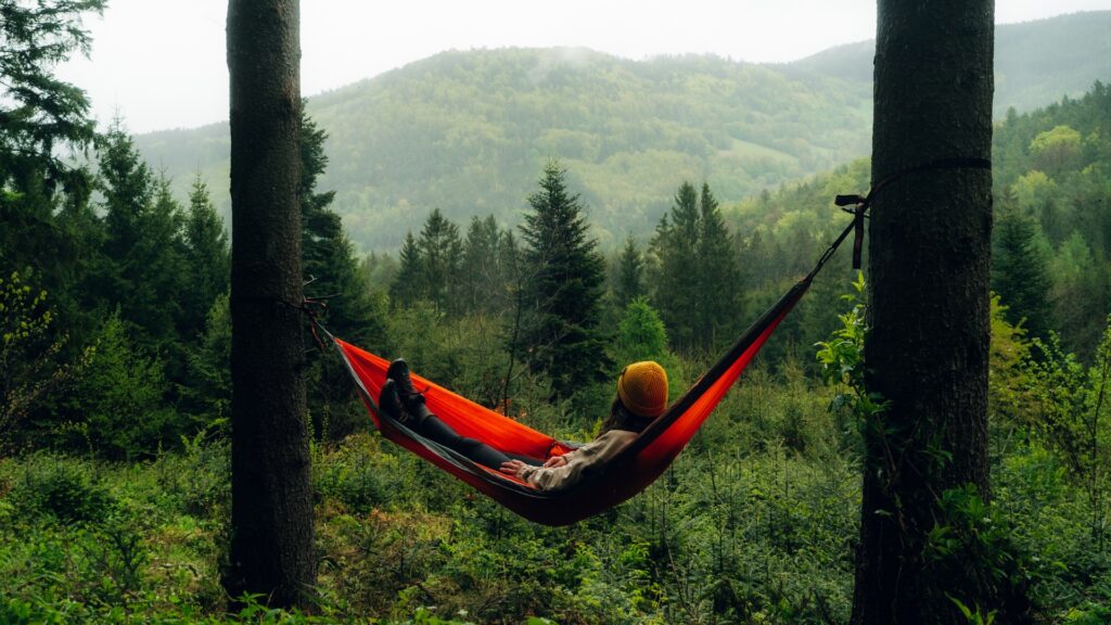 Frau liegt in Hängematte zwischen zwei Bäumen im Wald