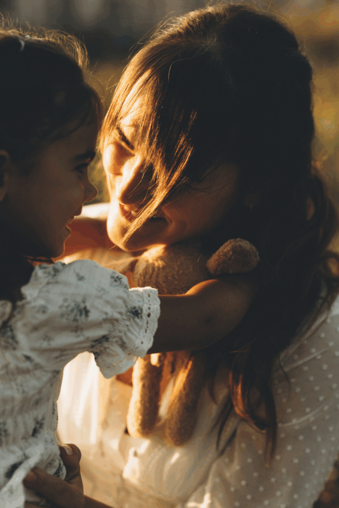 Eine Mutter und ihr Kind sehen sich an, die Tochter hat die Arme um den Hals der Mutter