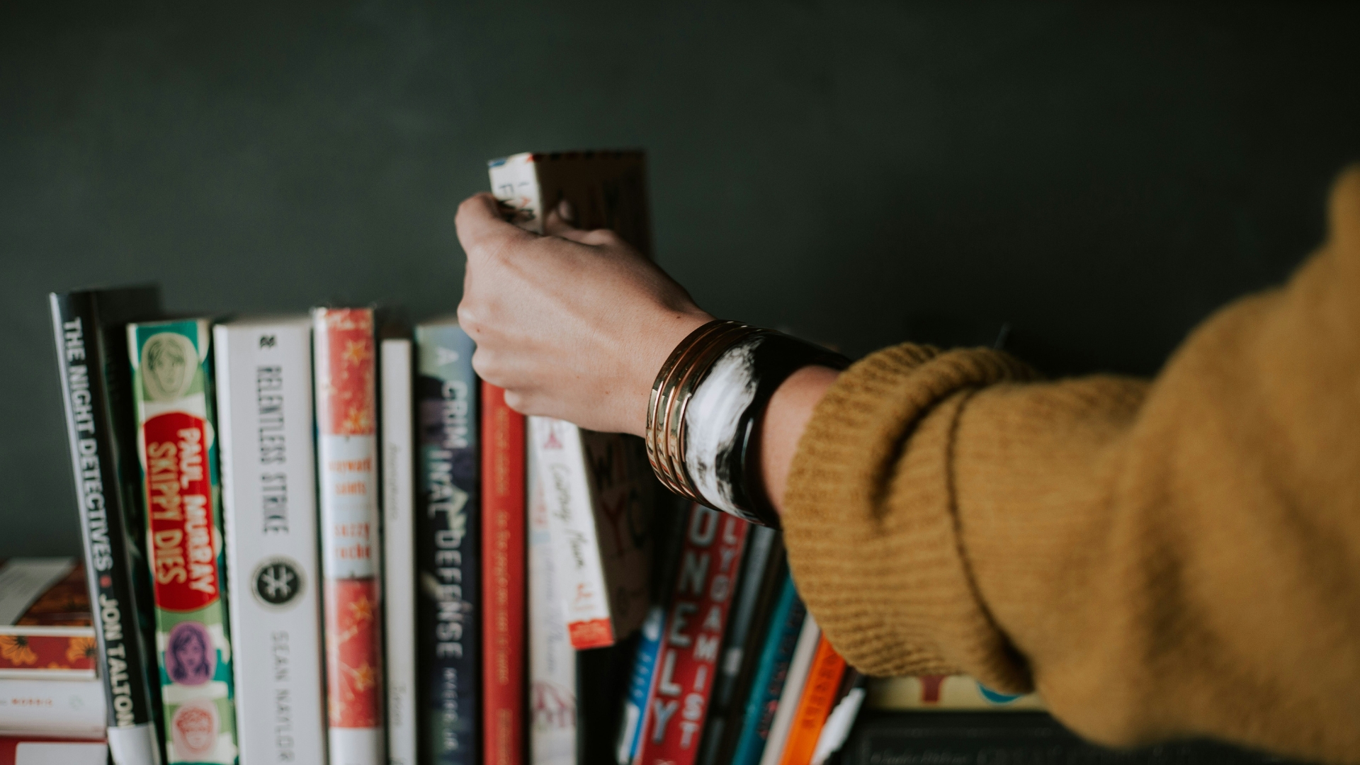 Frau nimmt Buch aus Bücherregal