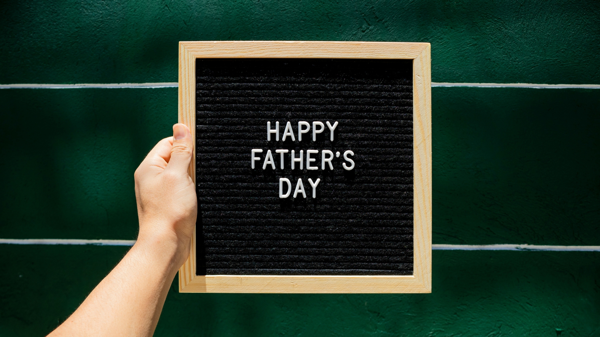 Happy Father's Day auf eine Tafel geschrieben, die von einer Hand gehalten wird