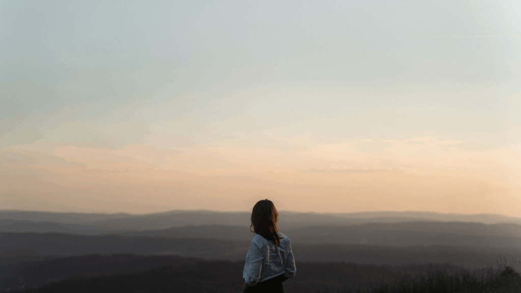 Eine Frau blickt bei Sonnenuntergang über den Horizont