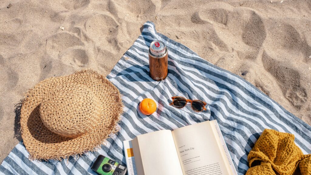 Strandtuch, Buch, Strohhut, Sonnenbrille, Getränk