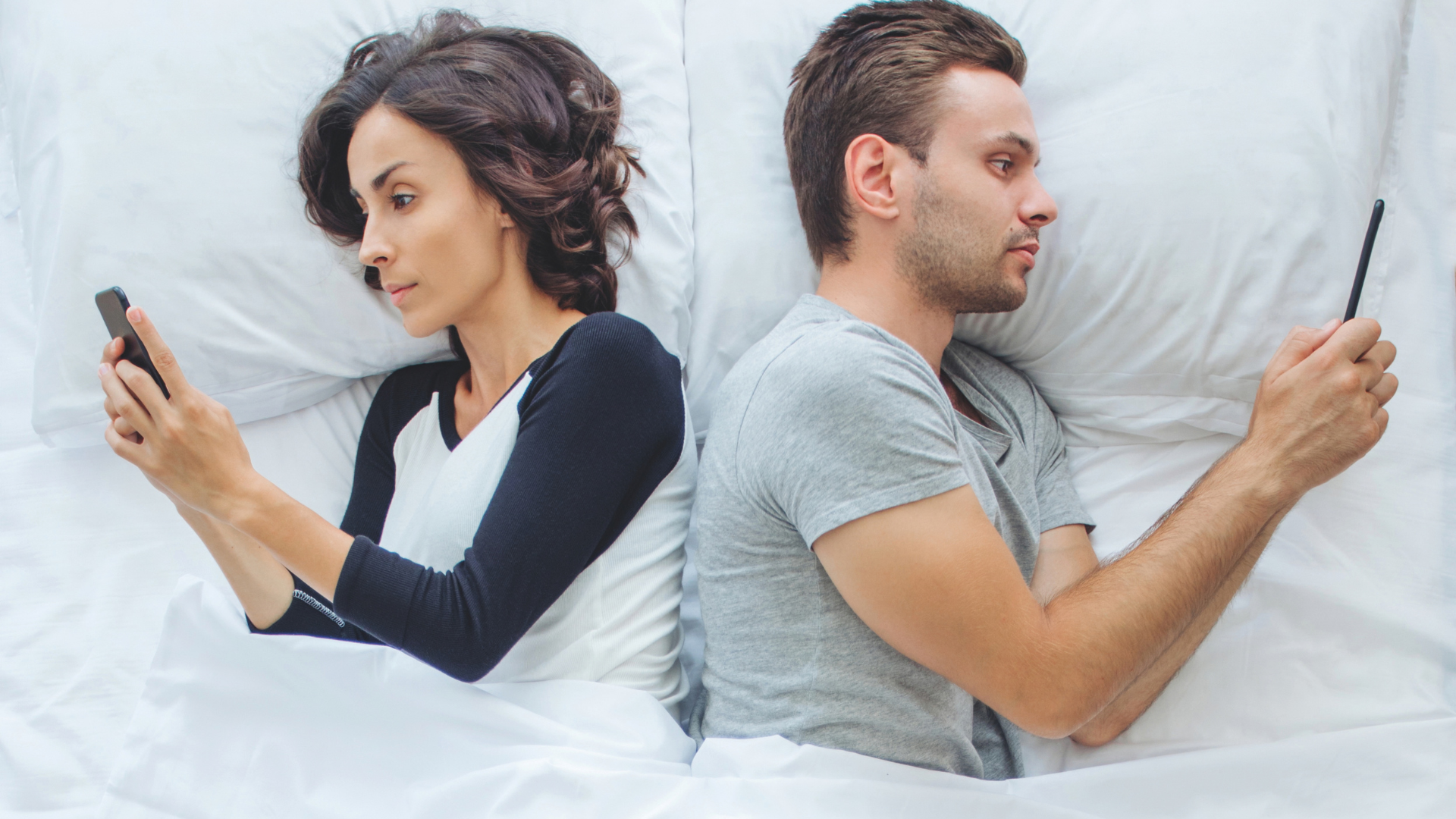 Liebe, Lust und Likes: Paar liegt mit dem Rücken zueinander gedreht im Bett und schauen jeweils auf das Handy